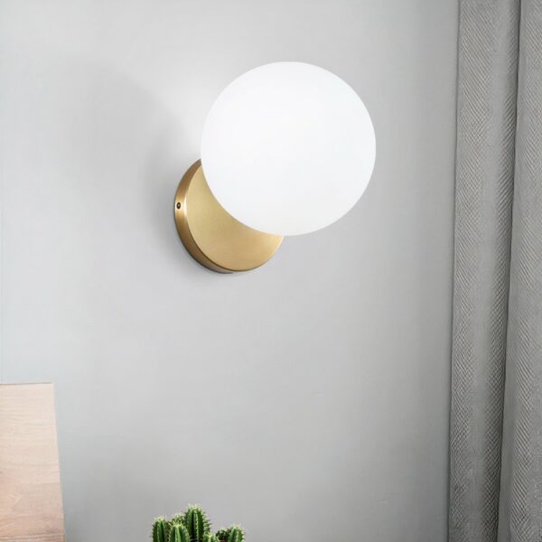 On a white background, we see a gold and white wall sconce in the shape of a lit glass ball.
