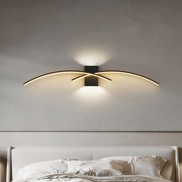 LED indoor wall light in modern, minimalist arc design for a bedroom above a bed