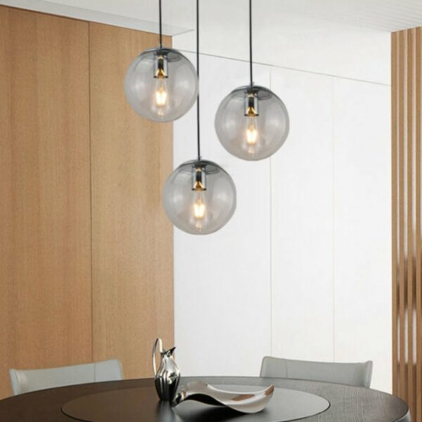 Modern black glass globe pendant presented 3 times above a dining table