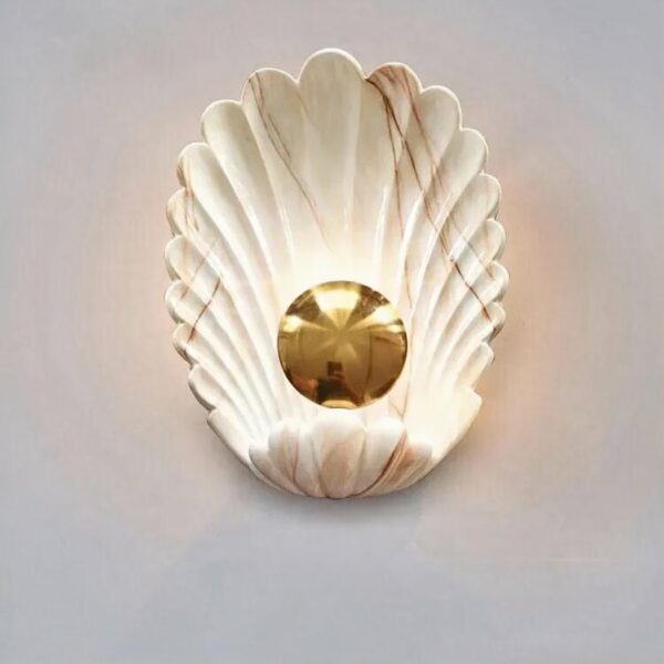 A white and gold shell-shaped wall sconce is set against a white background.