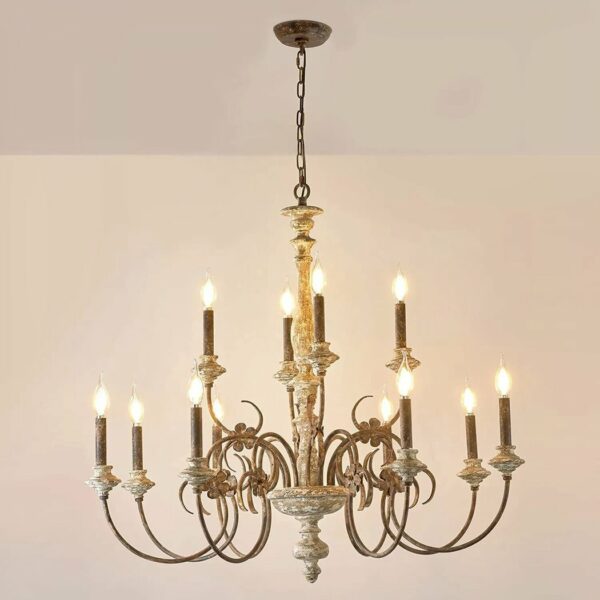 Brass and wood chandelier style with candles, the bulbs are like candle flames. They are lit. Suspended by a chain, the background is beige.