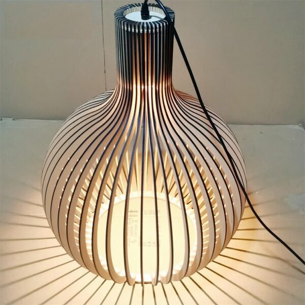 DIY solid bamboo chandelier, assembled and lit, on beige background.