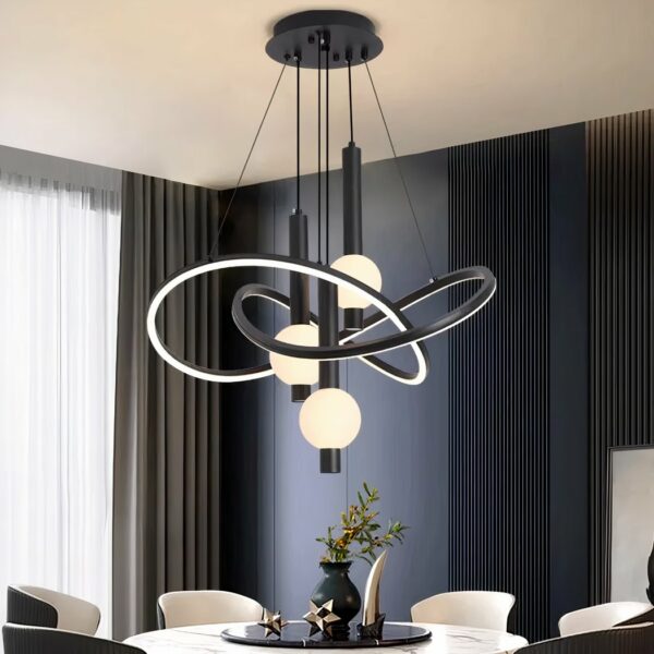 Black chandelier with black support fixed to the ceiling, from which cables descend to hold intertwined rounded structures that are luminous and black on the outside. In the center of these structures hang black tubes with a lighted ball. Fixed above a round white marble-style table with round black top, a vase on top and decorative objects. 6 armchairs around the table, to the left a bay window with a grey curtain and the wall opposite is duck-blue with vertical grooves.