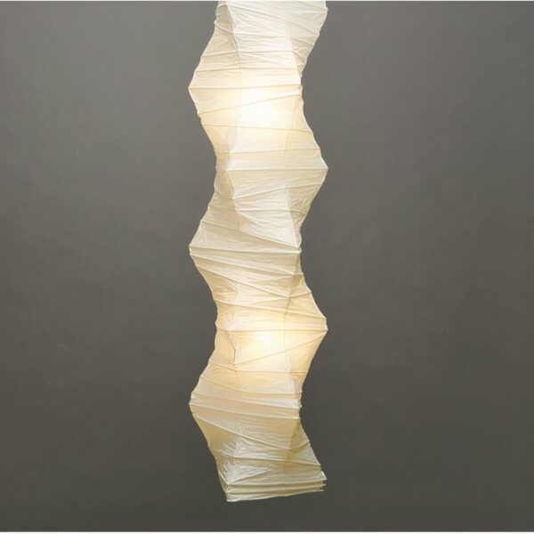 Large white Japanese pleated paper hanging lighted on a gray background.