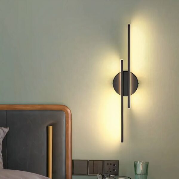 Modern design linear wall light hung on a bedroom wall and lit, next to the bed.