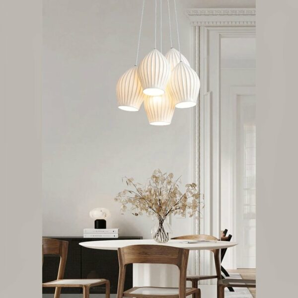 Multi-light pendant with five white ceramic shades set above a bonsai-decorated dining table on a gray background.