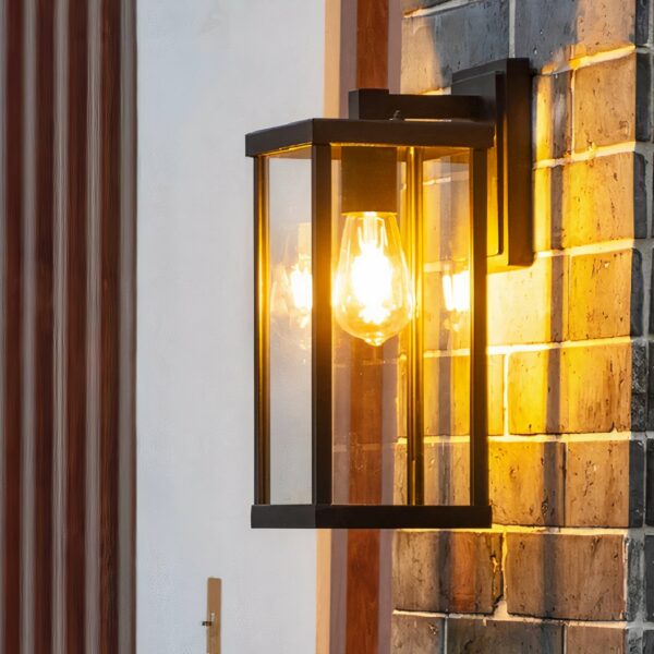 Retro aluminum and glass exterior wall sconce hung on an exterior brick wall and lit.
