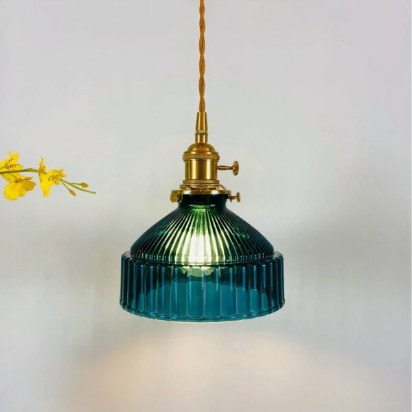 Vintage hanging lamp with twisted gold cable and gold lampholder, duck-blue bell-like shade with ridges all around. Light bulb on. Yellow flowers on left.
