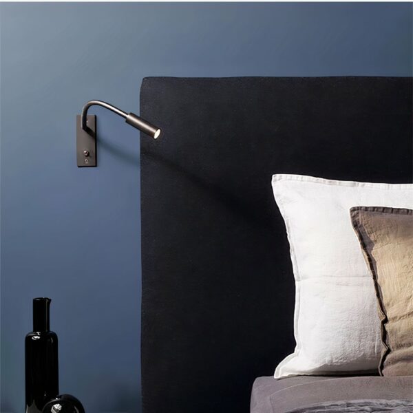 Wall-mounted reading light with switch, mounted on a blue bedroom wall next to a bed.