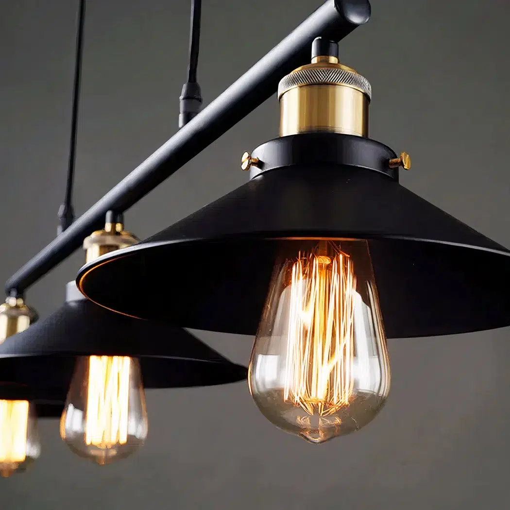 Close-up of black cone pendant shades with brass sockets and glowing filament bulbs