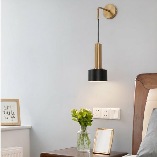 Lantern-style brass wall light in black and gold hanging next to a bed