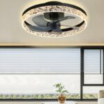 Black framed crystal ring ceiling fan glowing above large windows