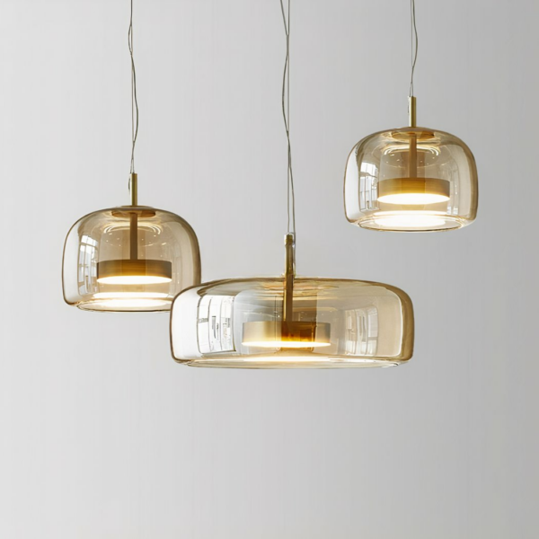 Trois luminaires en verre suspendus, un grand au centre et deux plus petits sur les côtés, celui de droite est plus haut que celui de gauche. Sur un fond gris.