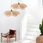 Two flower-petal shaped woven pendant lights above a leather chair near a staircase