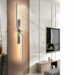 Zigzag linear LED wall light glowing on a wood panel beside a mirror