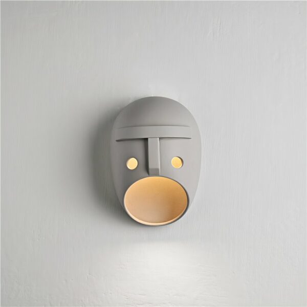 Ceramic wall lamp in the shape of a mask with yellow light inside its mouth
