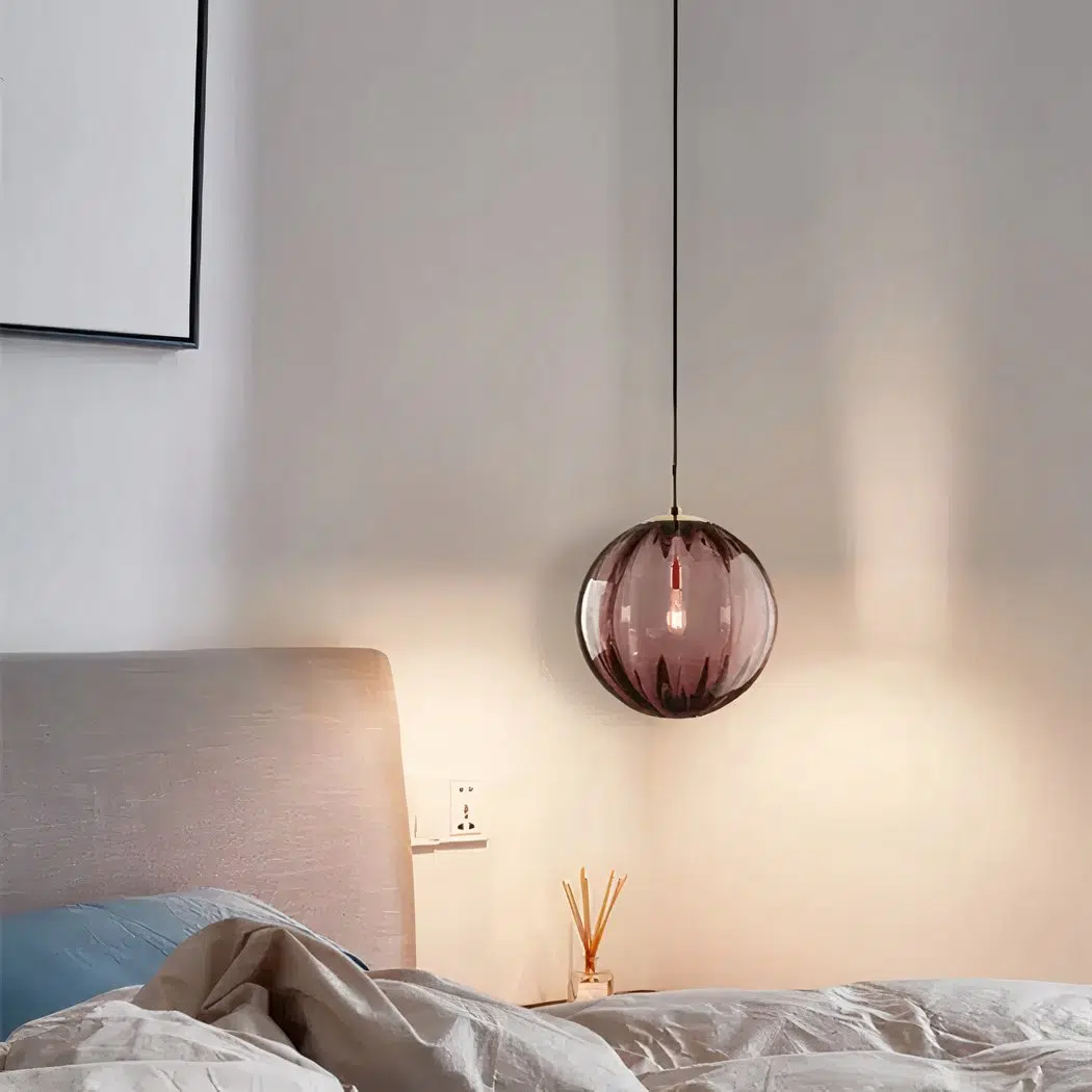 Plum coloured ribbed glass globe pendant light above a bedside table