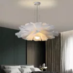 White acrylic layered flower pendant lit above a bed in a green panelled room