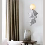 Resin monkey wall light covering its eyes beneath a round frosted glass globe