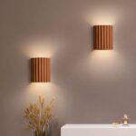 Two terracotta fluted wall lights lit above a console with wheat stems