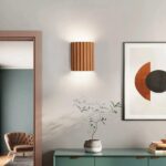 Terracotta fluted wall light lit beside a doorway and an abstract print