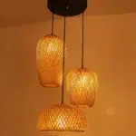 Three woven bamboo pendant lights of different shapes hanging from a black ceiling plate