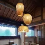 Three woven bamboo pendant lights hanging beneath a rustic wooden beamed ceiling