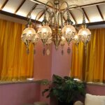 Moroccan-style brass chandelier with glass globes in a room with yellow curtains