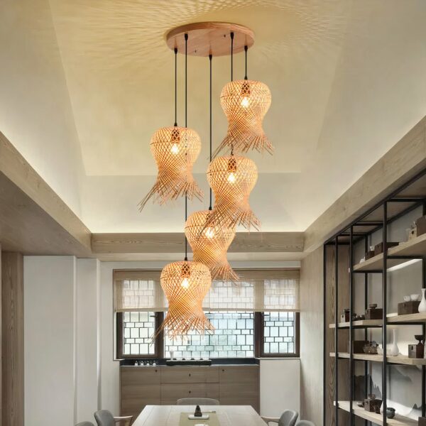 Hand-woven straw hat chandelier hanging from the ceiling and lit, above a dining room table.
