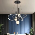 Black LED pendant light with interlocking loop shapes above a dining table