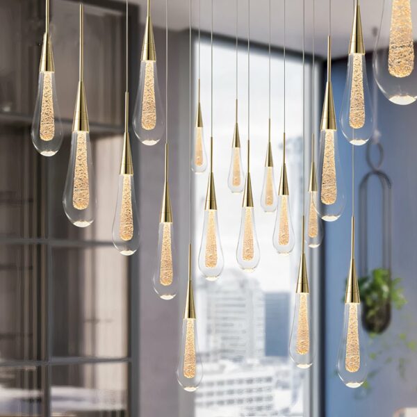 Cluster of teardrop shaped glass pendant lights with brass cone tops near a window