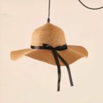 Pendant light shaped like a woven straw hat with a black ribbon bow, unlit