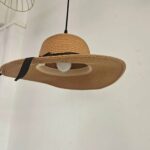 Underside view of the straw hat pendant light with a glowing bulb beneath the brim