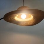 Close-up of the glowing straw hat pendant light showing its woven texture