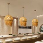 Three woven straw pendant lamps hanging above a restaurant counter with seating cushions