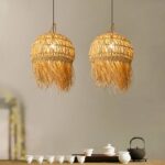 Two woven straw pendant lamps with a fringed edge hanging above a tea table