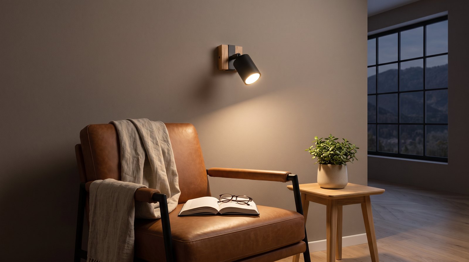 Industrial wall light in black metal and wood with an adjustable spotlight lighting a reading chair in the evening