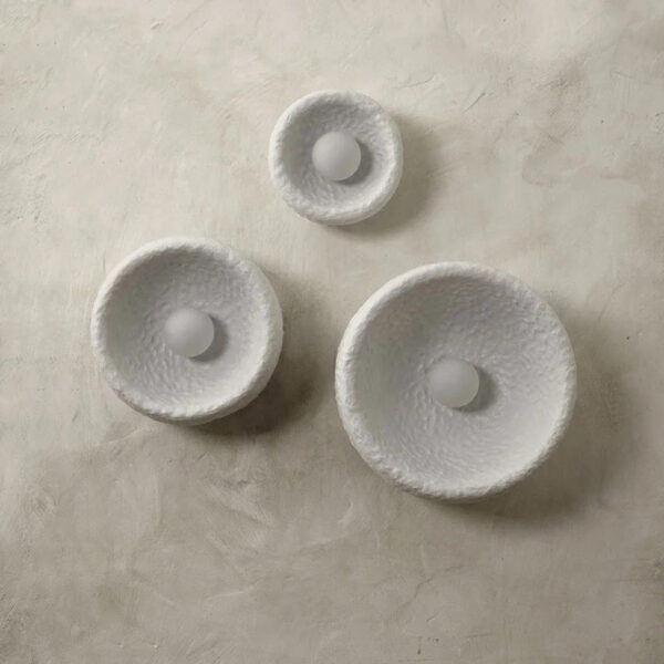 Three round textured white wall lights of different sizes with a small bulb each