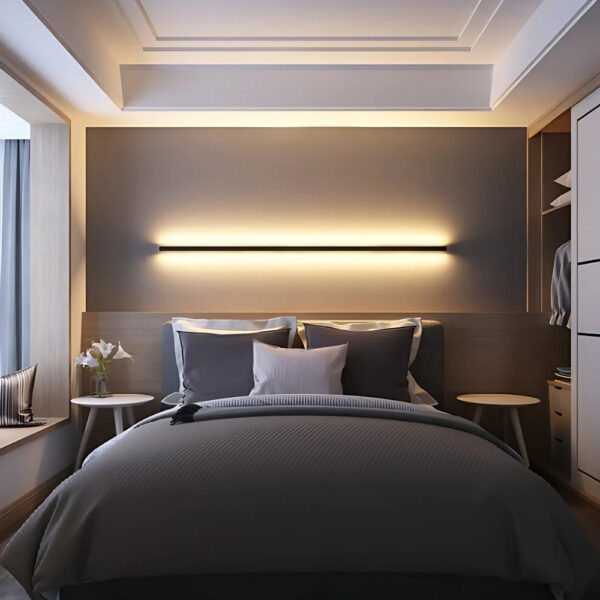 Minimalist black linear wall light glowing above a bed headboard