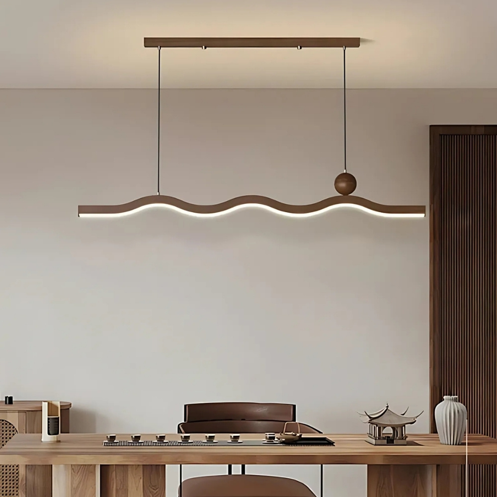 Dark wavy wood pendant light bar lit above a dining table with chairs
