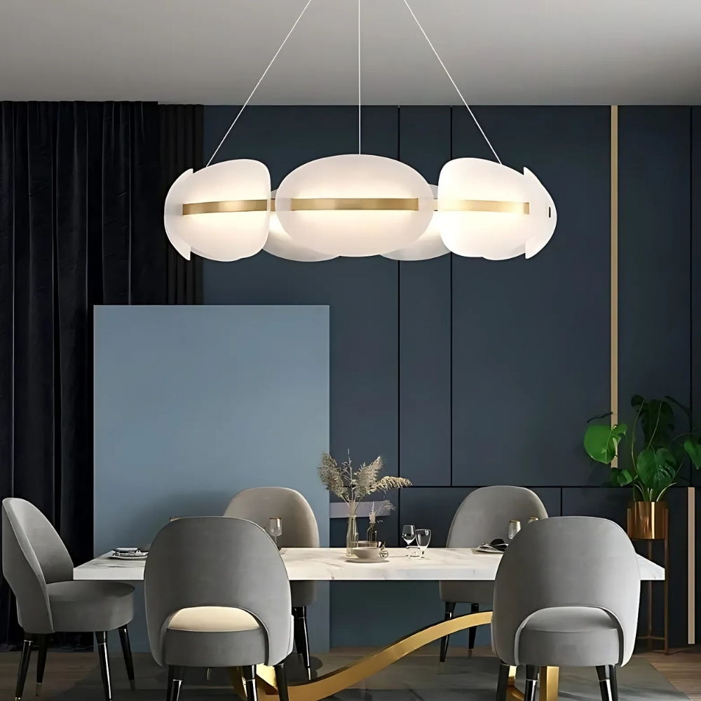 Shell-shaped brass chandelier glowing above a grey dining set in a navy room