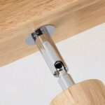 Detail of the chrome swivel joint fixing the wooden spotlight to the ceiling