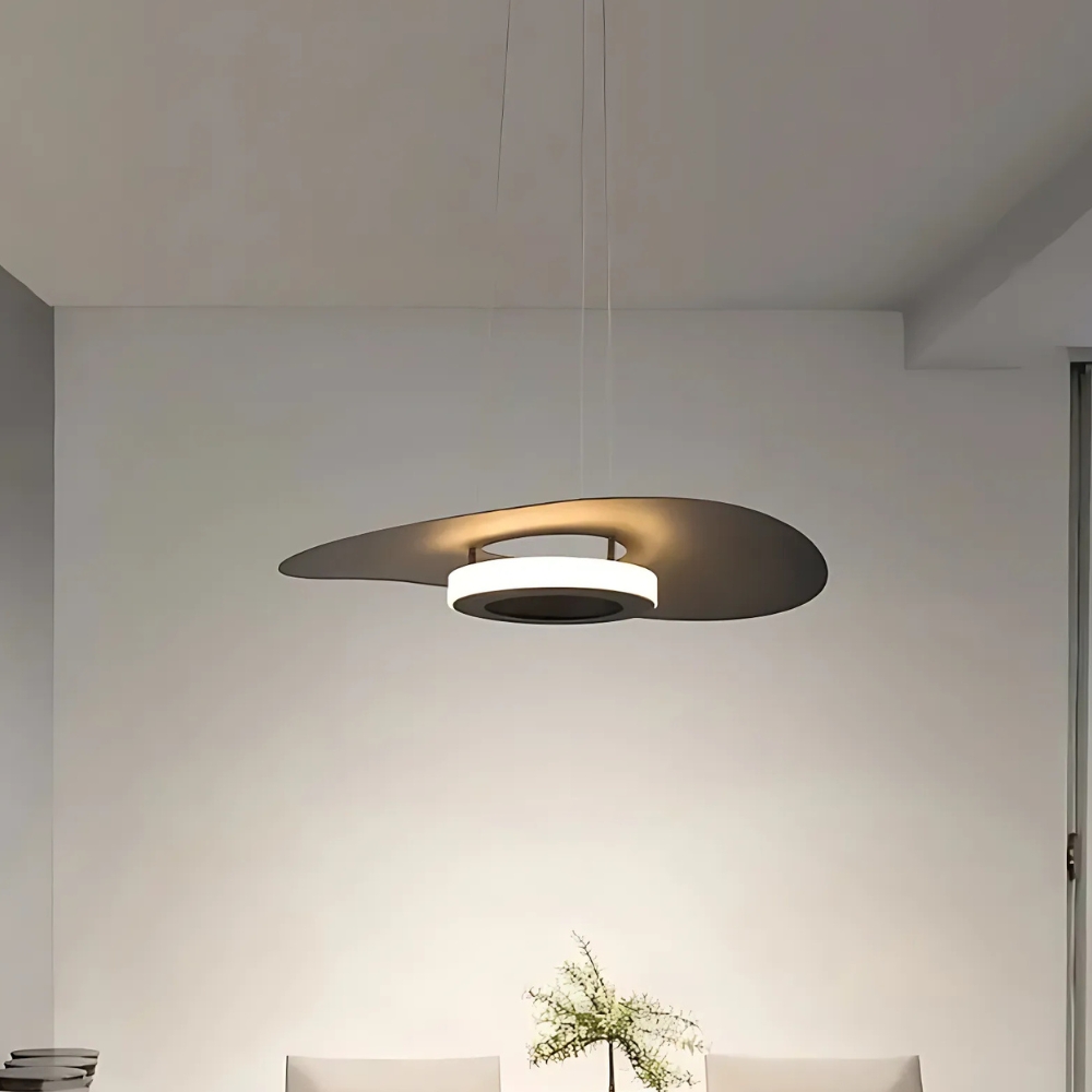 Single flat disc pendant glowing above a dining table against a plain wall