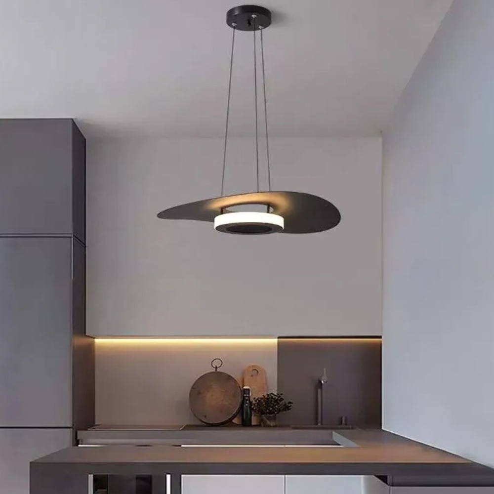 Flat disc pendant glowing above a dark kitchen counter and sink