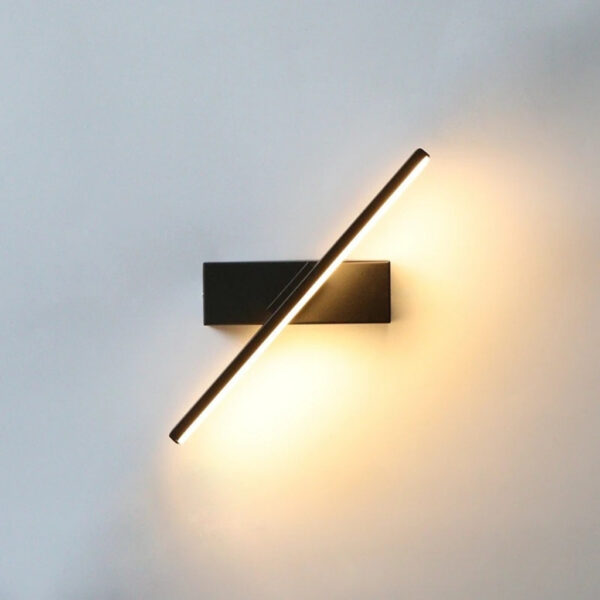 Black diagonal LED bar wall light casting a warm glow