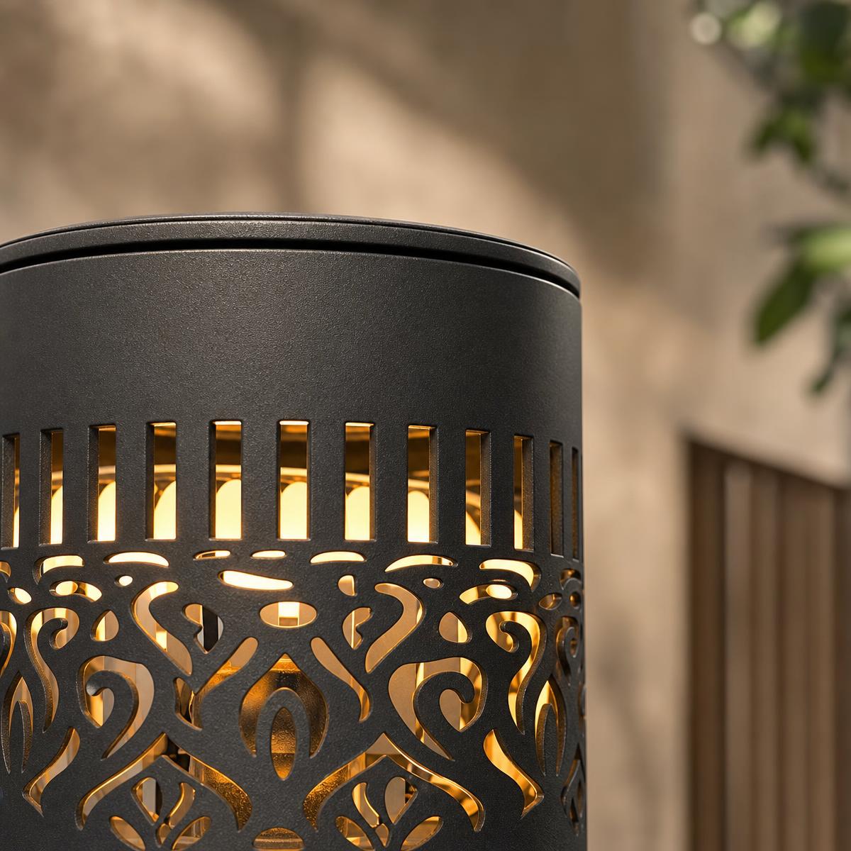 Close-up of the black cut-out lantern wall light glowing from an ornate pattern