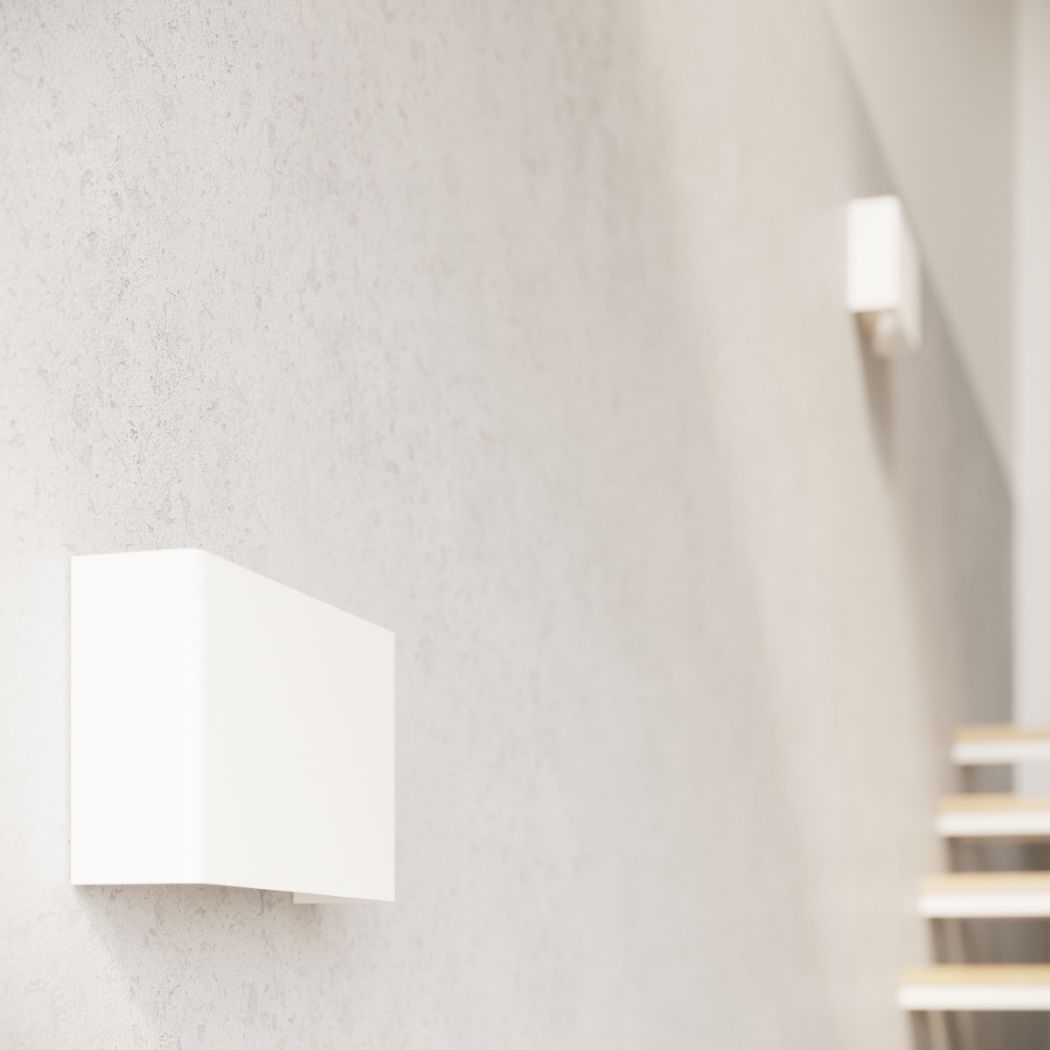 White angled folded wall light on a textured wall near a staircase
