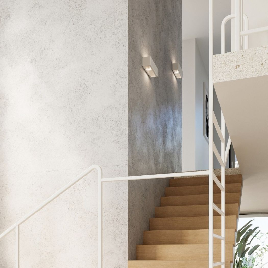 Two small white rectangular wall lights glowing on a two toned wall beside a staircase