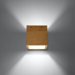 Cube shaped wooden wall light lit with light beams up and down