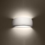 Glossy white half moon wall light glowing with light spreading up and down a dark wall